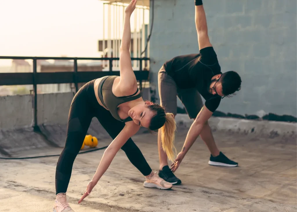 image of man and woman performing a dynamic cross body stretch in unison