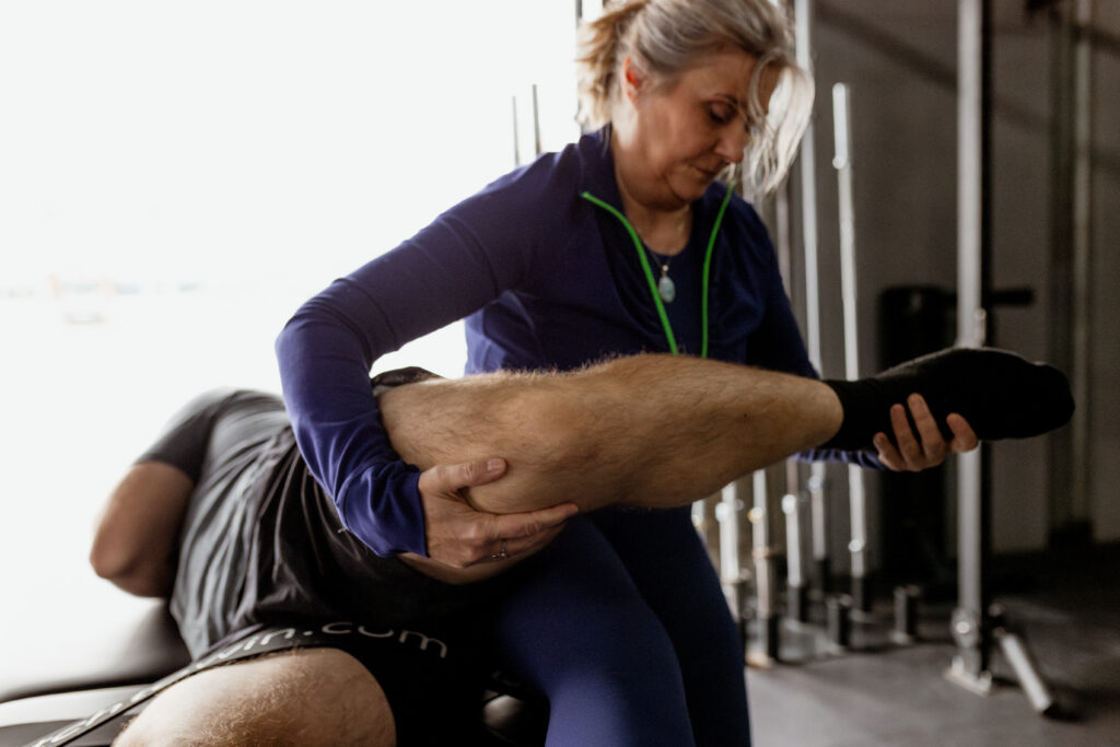 Hana Bland performing a deep hip flexor stretch with a male athlete during a Sports Fascia Stretch Therapy™ session.