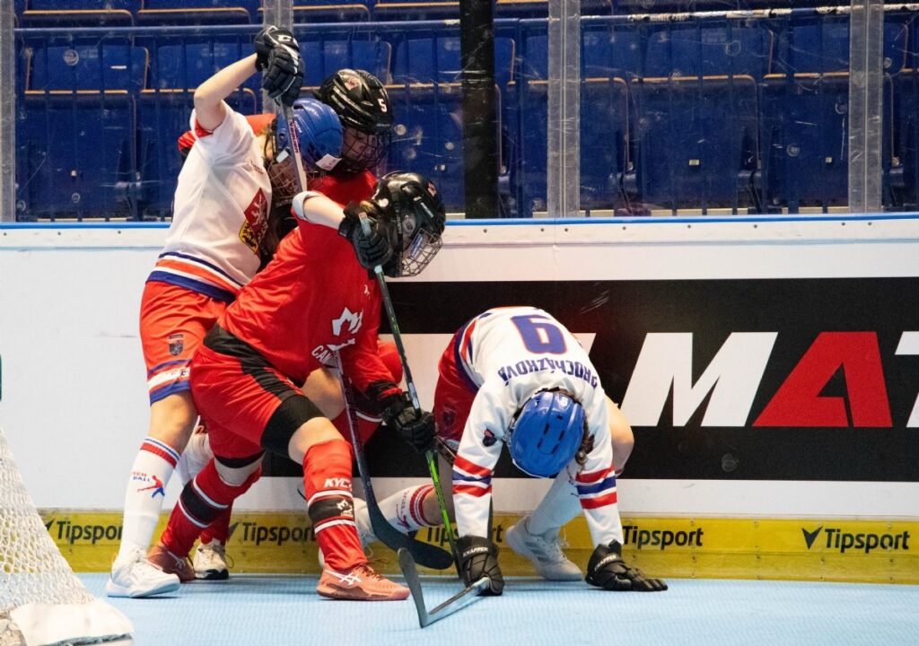 Canadian ball hockey players battling behind the net with Czech players during international competition.